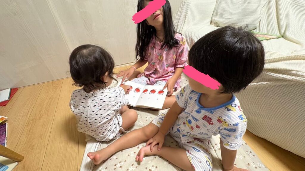 子ども３人が絵本を囲んでいる写真